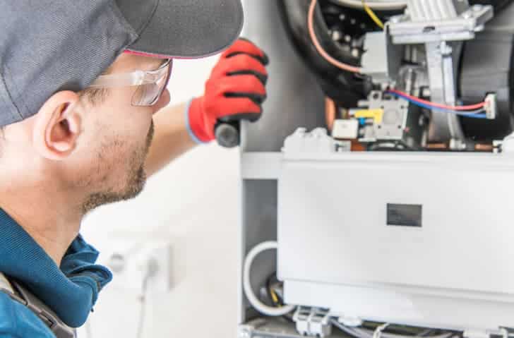 HVAC technician inspecting and repairing a residential furnace system