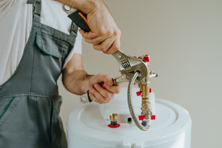 Plumber installing connections on a residential water heater using hand tools