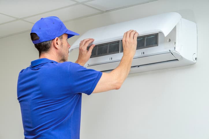 HVAC technician servicing a wall-mounted air conditioning unit