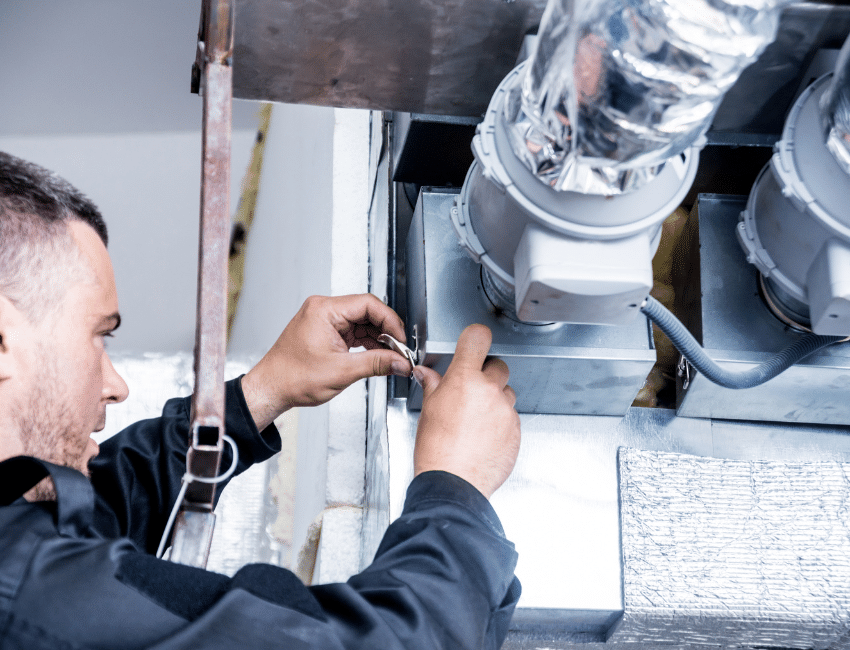 HVAC technician installing and servicing an air conditioning unit as part of a legal basement suite project in Alberta.