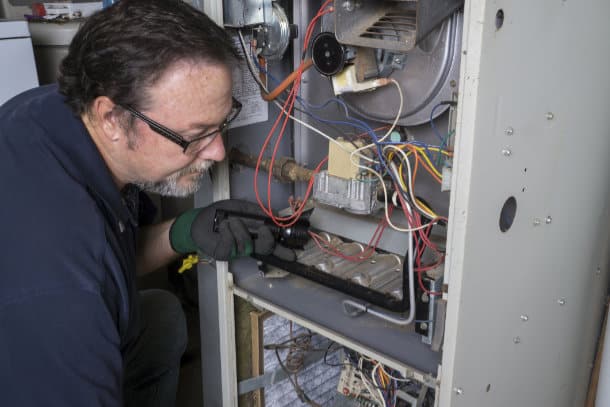 Furnace technician inspecting a gas furnace in Edmonton