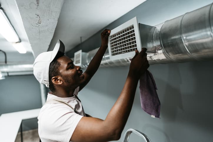 HVAC technician cleaning and installing an air vent on commercial ductwork